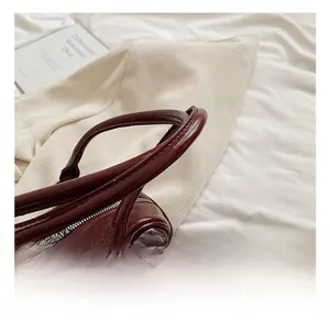 Detail showing high-gloss deep red leather tote with silver zipper and double handles