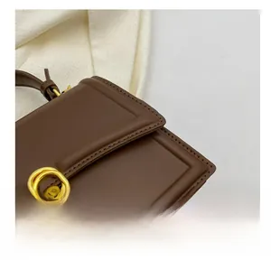 Detail shot of brown leather bag showing precise stitching and gold metal ring hardware