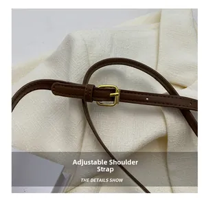 Macro detail of dark brown leather adjustable shoulder strap with gold metal buckle