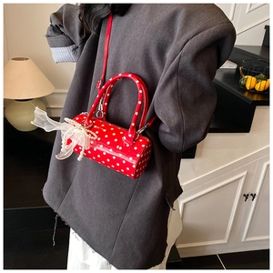 Detail of red polka dot barrel bag with pearl strand and translucent organza bow charm