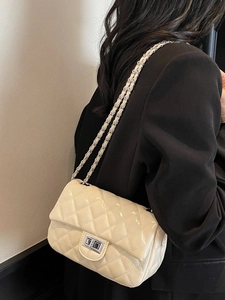 Beige quilted chain shoulder bag with silver lock worn over a black blazer for styling