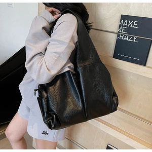 Detail of black large tote bag featuring soft pleated PU leather texture and wide strap