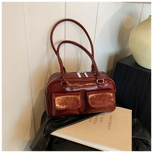 Close-up of deep burgundy patent leather shoulder bag with glossy finish and dual front pockets