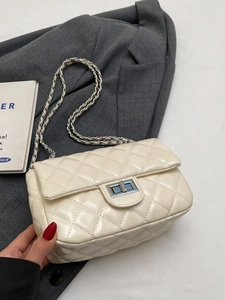 Elegant beige quilted crossbody chain bag with metal lock in a professional setting