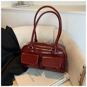 Detailed macro view of dark red glossy patent leather tote with silver hardware and pockets