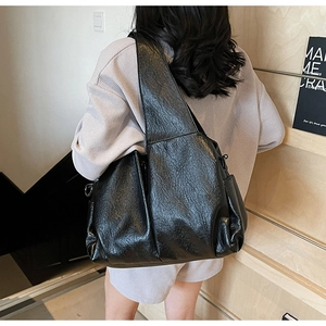 Detail of glossy wrinkled leather texture on black large capacity shoulder tote bag
