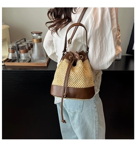 Detail of a straw and brown leather bucket bag with a drawstring closure and shoulder strap