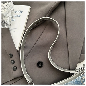 Detail of grey leather strap with white stitching and blue denim fabric on the bag