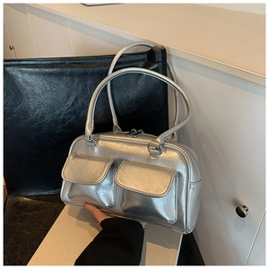 Detail of silver metallic tote bag featuring dual front flap pockets and smooth zipper closure