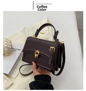 Detail of coffee brown square handbag featuring textured leather and gold U-shaped twist lock