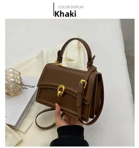 Detail view of khaki square handbag with golden twist lock and smooth leather texture