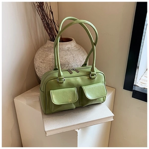 Close-up of green tote bag with two front flap pockets on minimalist prop set