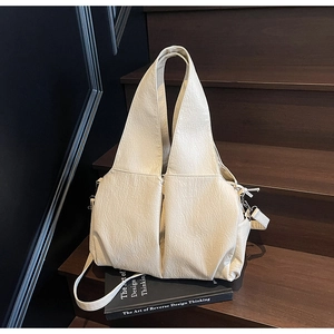 Detail of cream pleated leather bag with lychee texture and geometric folds on stairs