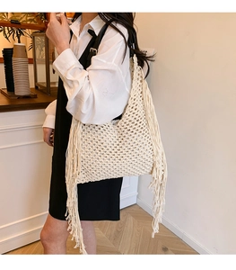 Close-up of beige crochet tote bag with woven fringe details and black leather strap
