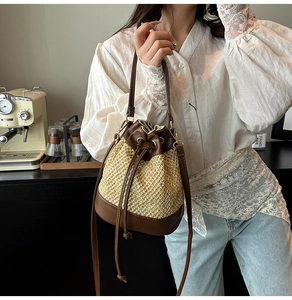 Detail of contrast stitch straw bucket bag with leather drawstring and strap in a lifestyle setting