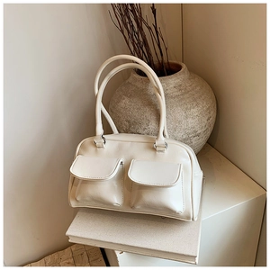 Chic cream leather tote bag featuring functional front flap pockets on a minimalist tray