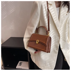 Brown leather crossbody bag with golden hardware shown in a professional business setting