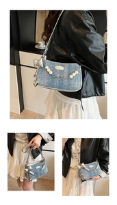 Detail of denim crescent bag with pearl chain, silver bow charms and metal zipper