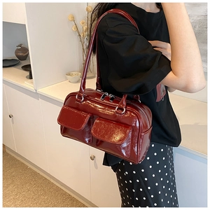 Close-up of deep red glossy patent leather tote bag with silver zippers and pockets