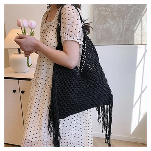Detailed view of black crochet woven tote bag with long bohemian tassels and hollow grid texture