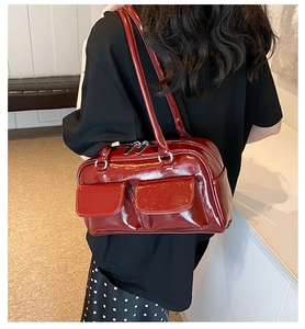 Detailed view of a red patent leather shoulder bag with dual front flap pockets