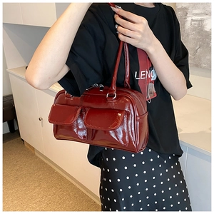 Detail of burgundy glossy patent leather tote bag with dual front pockets and stitching
