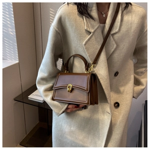 Close-up of brown vintage leather handbag with gold ring clasp on model in wool coat