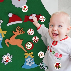 DIY Filz-Weihnachtsbaum-Set mit bunten Wichtel-Aufklebern und spielendem Baby bei der Dekoration