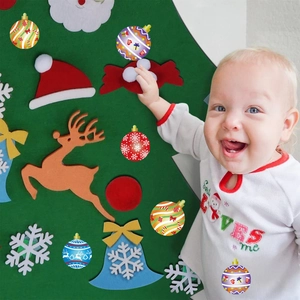 Détail d'un bambin interagissant avec un sapin de Noël en feutre et des décorations