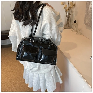 Close-up of a glossy black underarm tote bag with functional front flap pockets