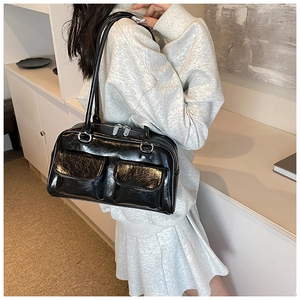 Close-up of black glossy shoulder bag featuring double front pockets and silver hardware