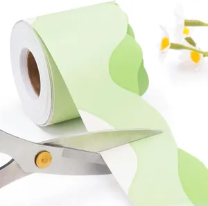 Close-up of light green scalloped bulletin board border sticker being cut with scissors
