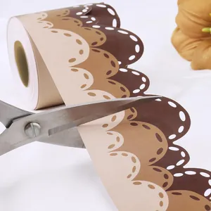 Close-up of wavy brown bulletin board border sticker being cut with scissors on white fabric