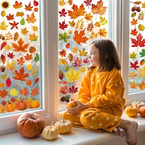 Bambina che decora la finestra con adesivi autunnali di foglie di acero e zucche vivaci