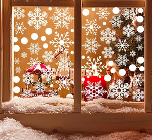 Close-up of white snowflake window clings on glass with a festive winter home background