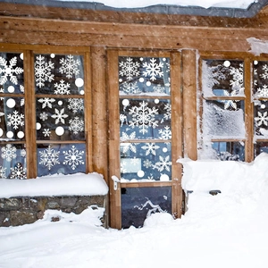 Detailed white snowflake static window decals applied to a glass window with snowy background