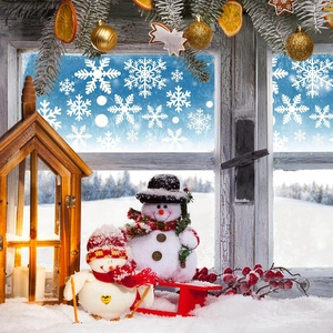 Detailed view of white snowflake window stickers on glass with a warm winter scene