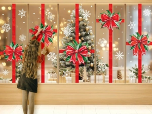 Detail of a child applying large red bow and snowflake window stickers for Christmas