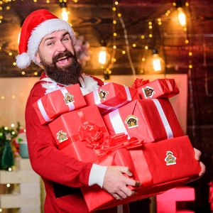 Man holding red Christmas gift boxes decorated with cute gingerbread house stickers