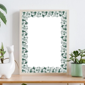 Green watercolor pine tree forest art frame on a wooden shelf in a bright room