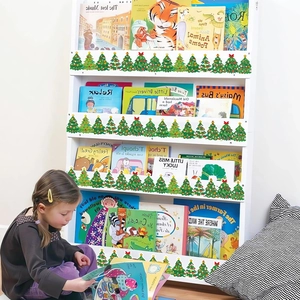 Child using white 4-tier bookshelf with green Christmas tree trim and storybooks