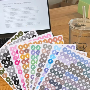 Macro shot of colorful round alphabet stickers with A-Z letters on a wooden desktop