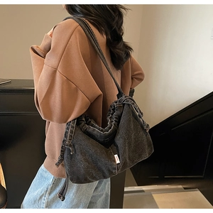 Détails du sac fourre-tout en denim gris avec plis de serrage et étiquette latérale