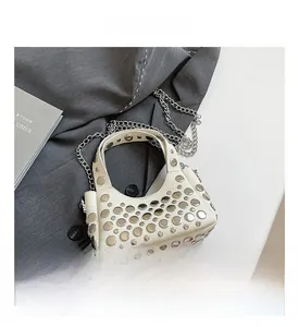 Dettaglio borsa beige motivo litchi con borchie argentate e tracolla a catena in metallo