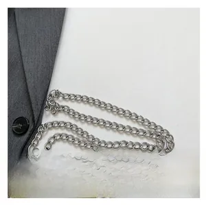 Dettaglio del cinturino in pelle bianca con borchie argentate e catena in metallo industriale