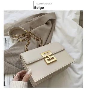 Détail du sac bandoulière beige avec boucle carrée dorée et bandoulière chaîne sur tissu