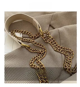 Détail de la bandoulière en chaîne dorée et coussinet en cuir beige pour sac à main femme