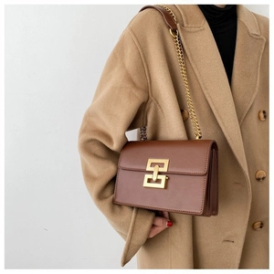Détail d'un sac à bandoulière en cuir marron avec fermoir doré et bandoulière chaîne