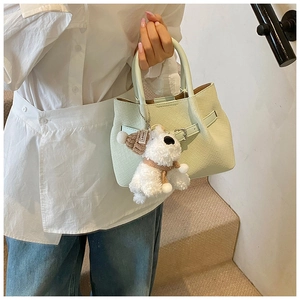 Détail du sac panier tressé vert menthe avec un adorable pendentif chien en peluche