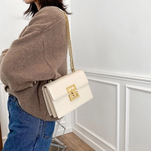 Détail du sac à bandoulière crème avec fermoir carré doré porté par un mannequin